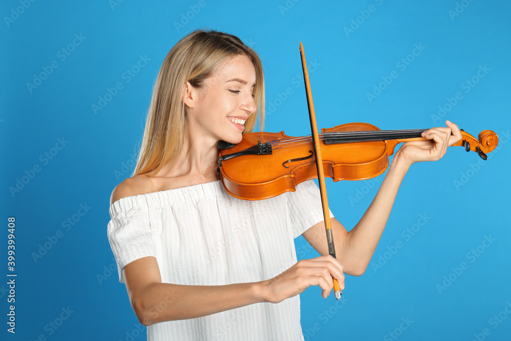 Beautiful woman playing violin on blue background Beautiful woman playing violin on blue background
