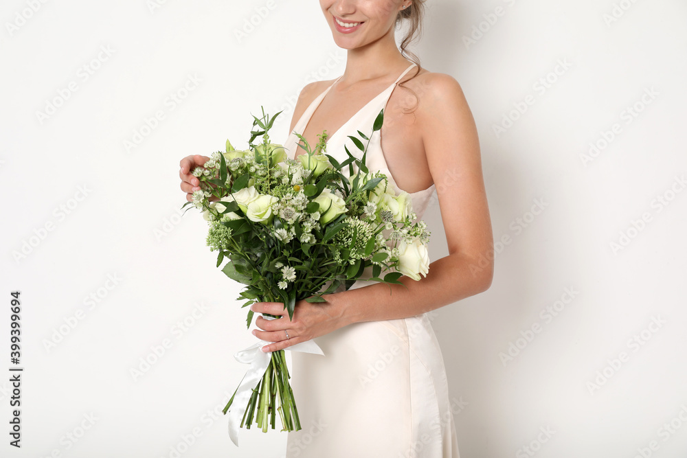 Young bride wearing wedding dress with beautiful bouquet on light background, closeup Young bride wearing wedding dress with beautiful bouquet on light background, closeup