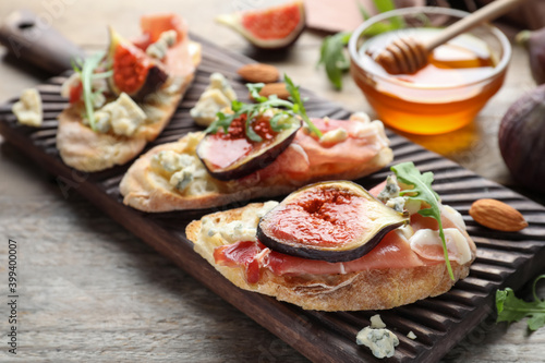 Sandwiches with ripe figs and prosciutto served on wooden table, closeup