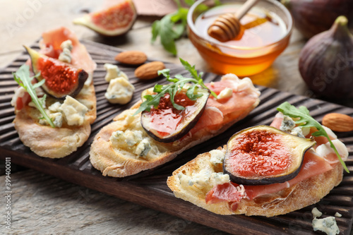 Sandwiches with ripe figs and prosciutto served on wooden table, closeup