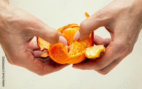 Close-up of female hands brushing tangerine on white background