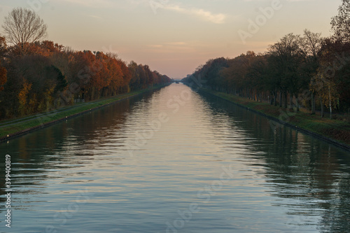 View from bridge over long straight canal at autumn evening