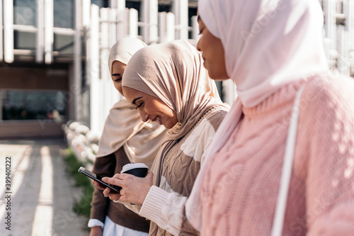 Three muslim women looking at smartphone. photo