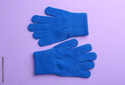 Pair of stylish woolen gloves on violet background, flat lay