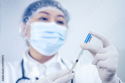 Selective focus, The COVID-19 vaccine is ready for use. Female Doctor with a stethoscope on shoulder holding syringe and COVID-19 vaccine.