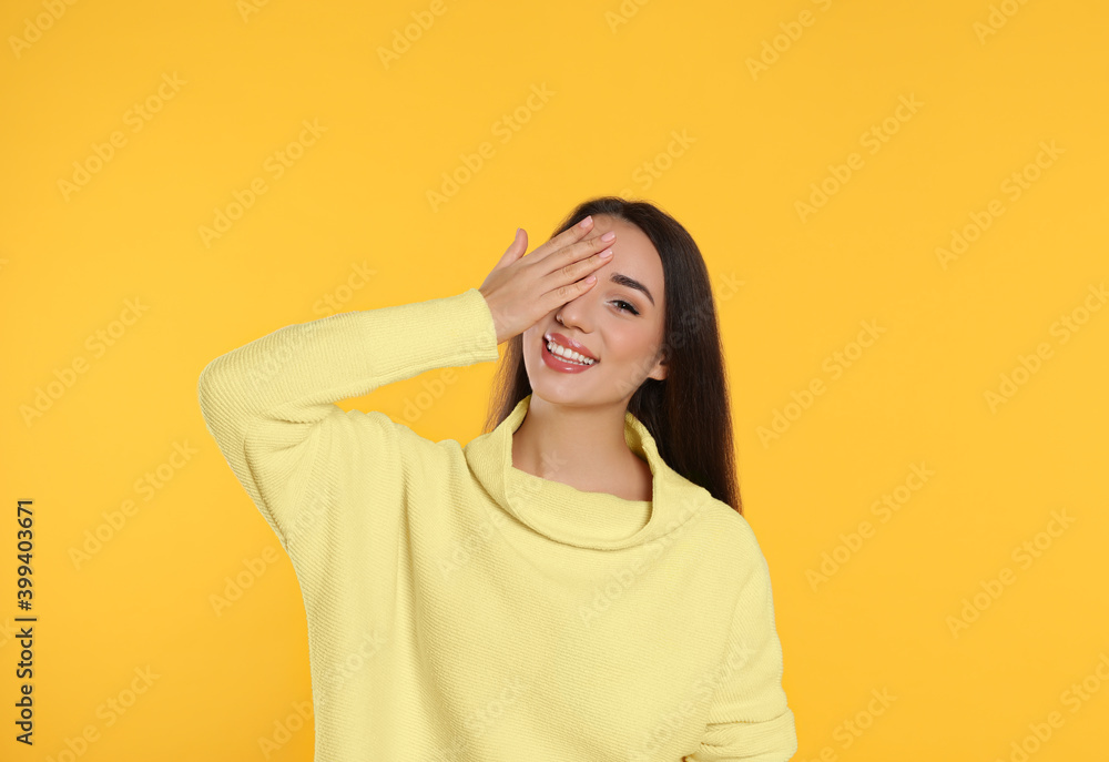 Beautiful young woman wearing warm sweater on yellow background Beautiful young woman wearing warm sweater on yellow background