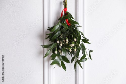 Canvas Print Mistletoe bunch with red ribbon hanging on light background