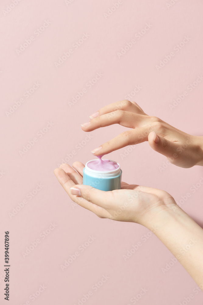 Beautiful young woman hands holding a jar of cream, isolated on a pink background Beautiful young woman hands holding a jar of cream, isolated on a pink background