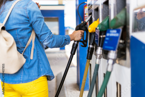 Unrecognizable woman holding fuel nozzle to refuel oil for car