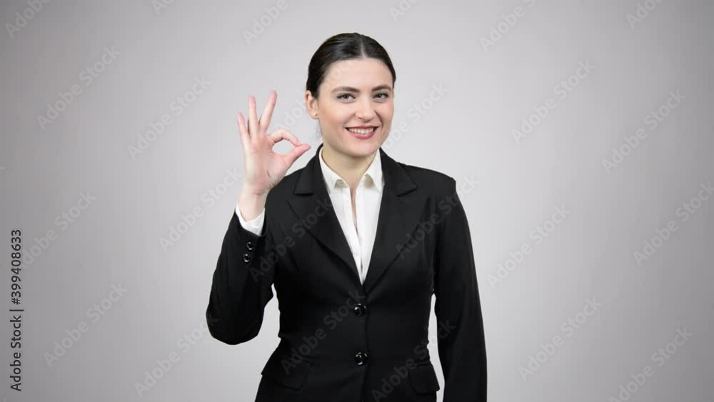 Happy business woman wearing a black suit with a white shirt saying OK Happy business woman wearing a black suit with a white shirt saying OK