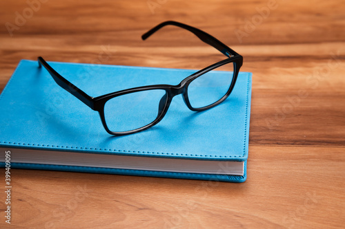 black glasses on blue book in wooden table