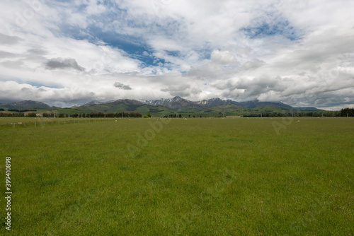 Green field under cloudscape in Te Anau Downs, New Zealand photo