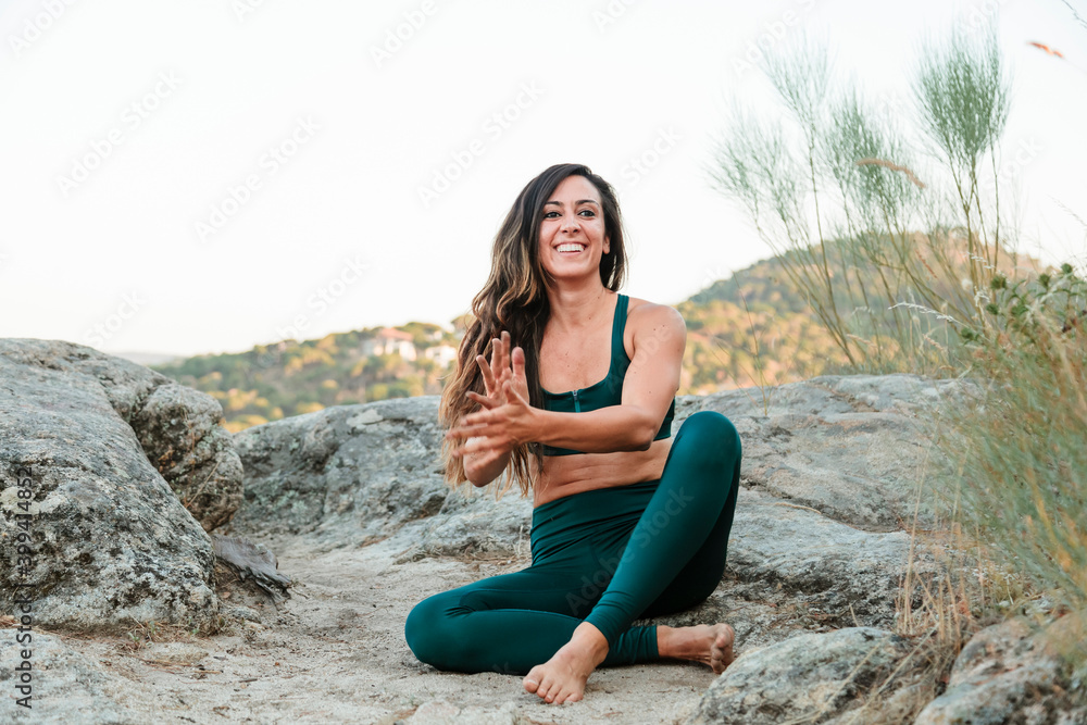 Happy beautiful woman shaking dust off her hands while sitting on mountain against clear sky Happy beautiful woman shaking dust off her hands while sitting on mountain against clear sky