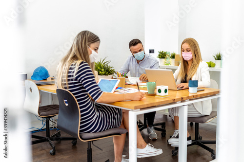 Business people wearing face mask while sitting by desk at office