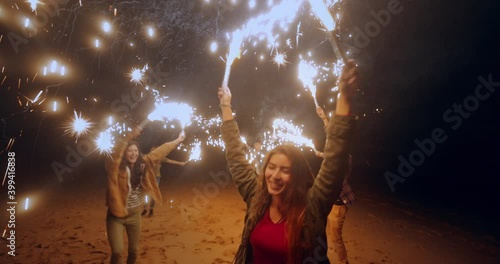 Group of friends having fun with sparklers at the beach