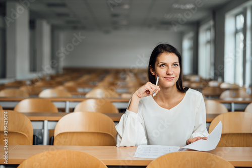 Knowledgable female student taking an easy exam in an empty amphitheater. An optimistic student taking an in-class test. Happy woman having stress free education evaluation.Essay exam inspiration. photo