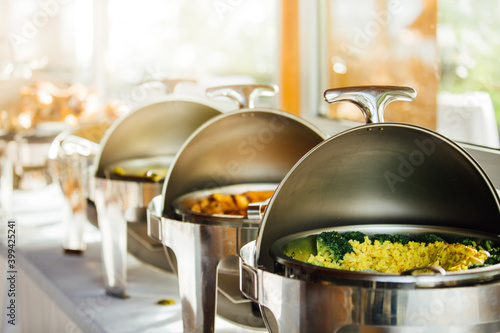 Elegant chafing dishes and food warmers with various meals served for catering reception in hotel or restaurant. Buffet served by the catering service company. Appetizers in elegant serveware.