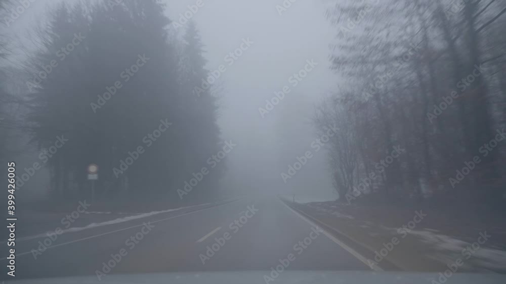 Driving through a foggy and snowy countryside on a spooky and slippery road with reduced visibility point of view during winter in Bavaria, Germany. Driving through a foggy and snowy countryside on a spooky and slippery road with reduced visibility point of view during winter in Bavaria, Germany.