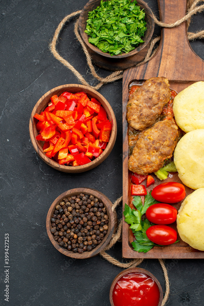 Vertical view of tasty cutlets chopped vegetables greens for dinner on dark background Vertical view of tasty cutlets chopped vegetables greens for dinner on dark background