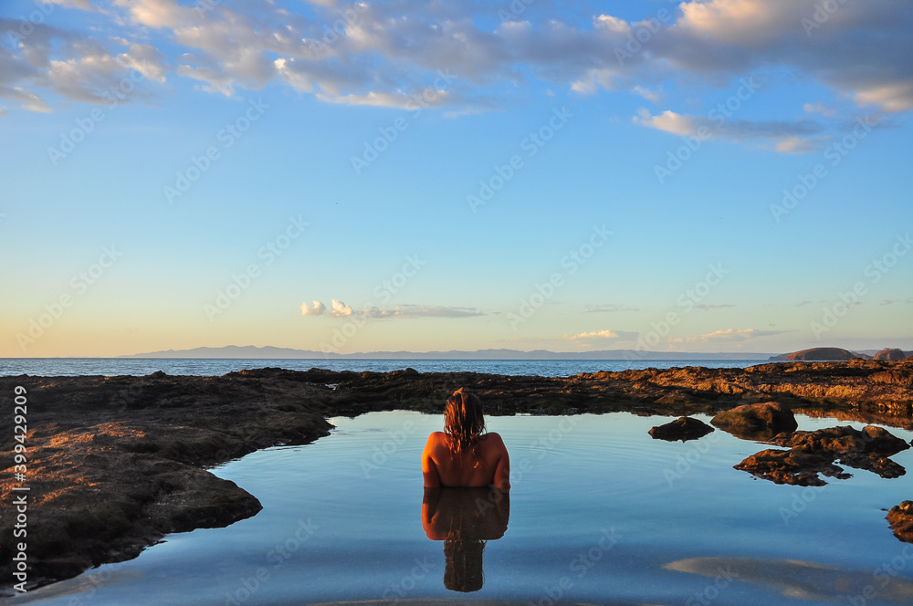 woman looking to the horizon in a natural pool inside the sea 