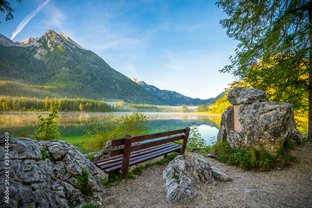 Empty bench on sunny morning at Hintersee lake. Bavarian alps 