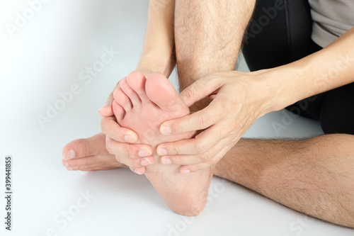 Foot Pain  young man sitting on the bed at home   he holding  feet press massage . Concepts of pain and health therapy.