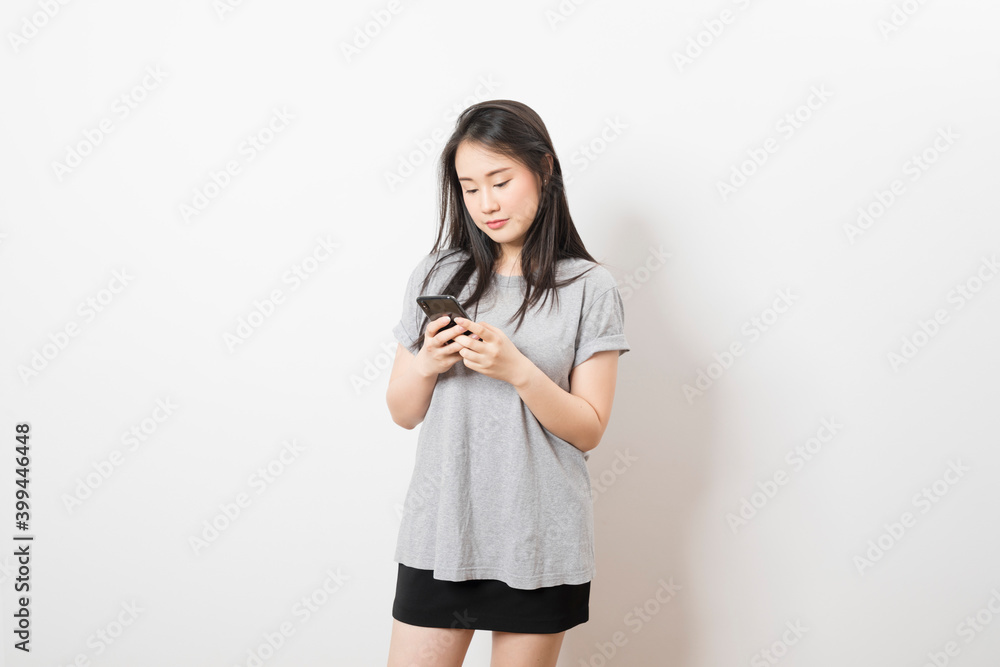 Beautiful Asian woman standing and smile using mobile smart phone looking to camera on a white background. Beautiful Asian woman standing and smile using mobile smart phone looking to camera on a white background.
