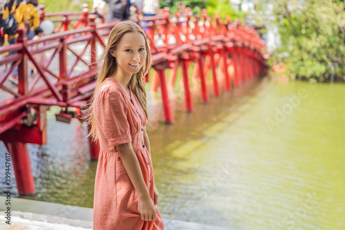 Caucasian woman traveler on background of Red Bridge in public park garden with trees and reflection in the middle of Hoan Kiem Lake in Downtown Hanoi. Vietnam reopens after coronavirus quarantine