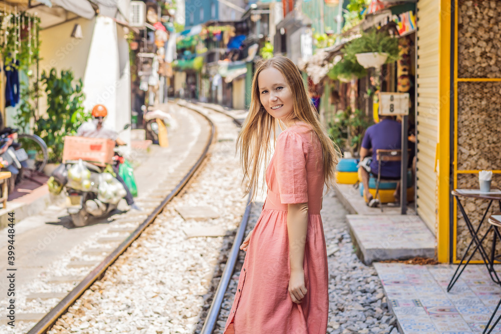 Woman is walking of Hanoi city railway. Perspective view running along narrow street with houses in Vietnam. Hanoi train street, old house and railroad. Vietnam reopens after coronavirus quarantine