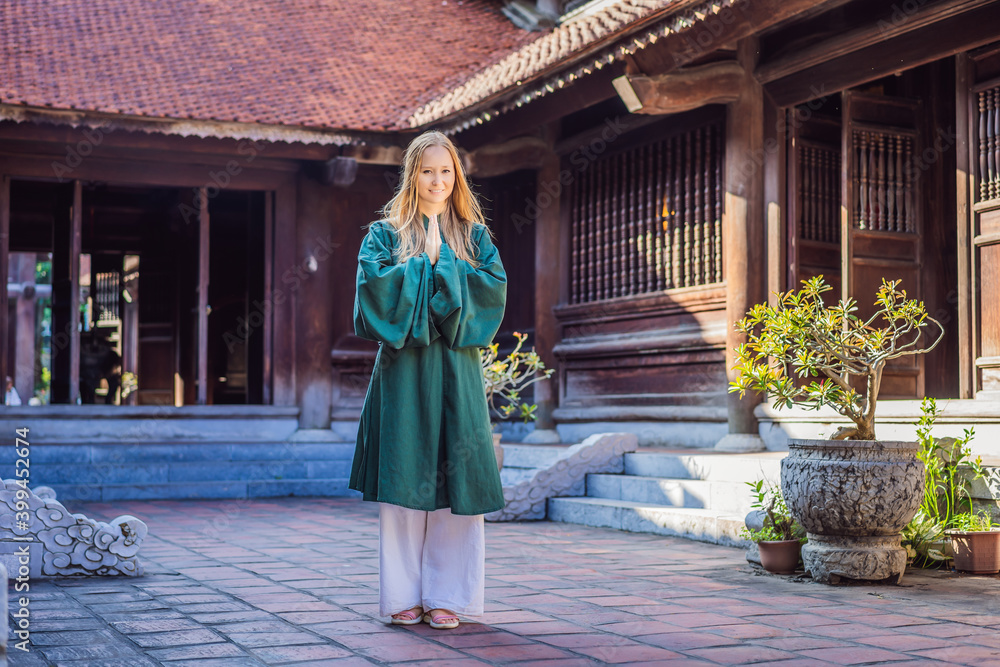 Naklejka premium Woman tourist in national vietnamese dress in Temple of Literature in Hanoi in Southeast Asia, Vietnam. Vietnam reopens after coronavirus quarantine COVID 19