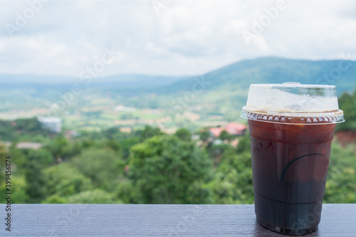 Iced coffee on wooden table on mountain view background
