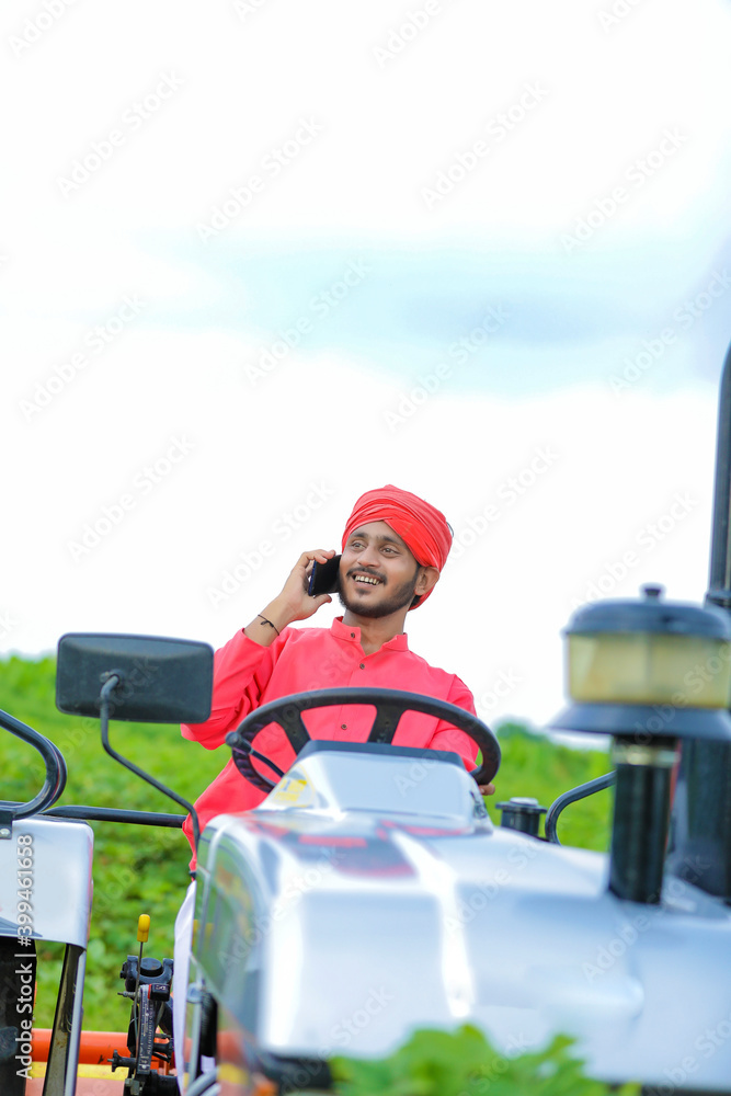 Young Indian farmer talking on smartphone at field