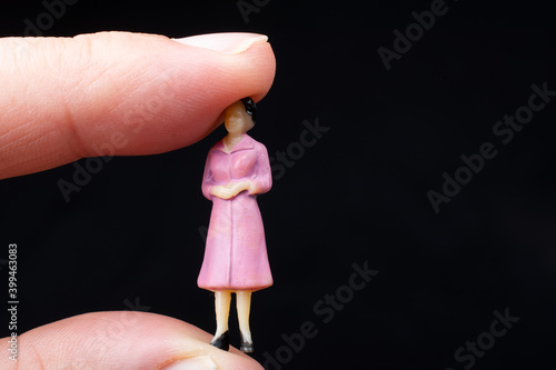 miniature figurines of a woman sitting betwee the finger of a hand photo