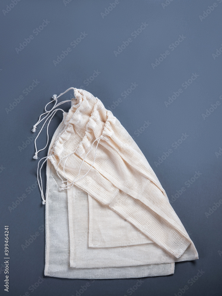 Three white zero waste string sacks for fruits, vegetables, grocery or other products on the grey background with the empty space for your text. Three white zero waste string sacks for fruits, vegetables, grocery or other products on the grey background with the empty space for your text.