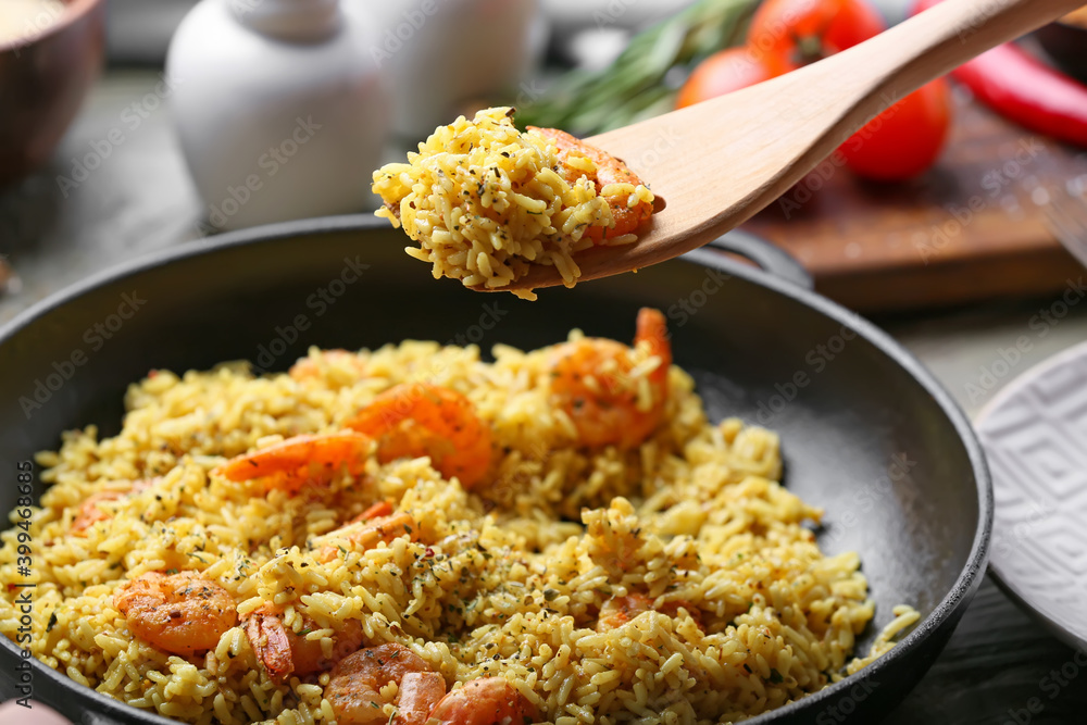 Frying pan with tasty pilaf and wooden spoon Frying pan with tasty pilaf and wooden spoon