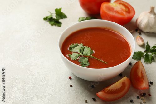 Bowl with tomato soup and ingredients on light background