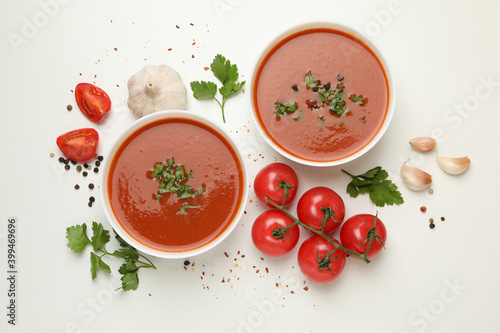 Bowls with tomato soup and ingredients on white background