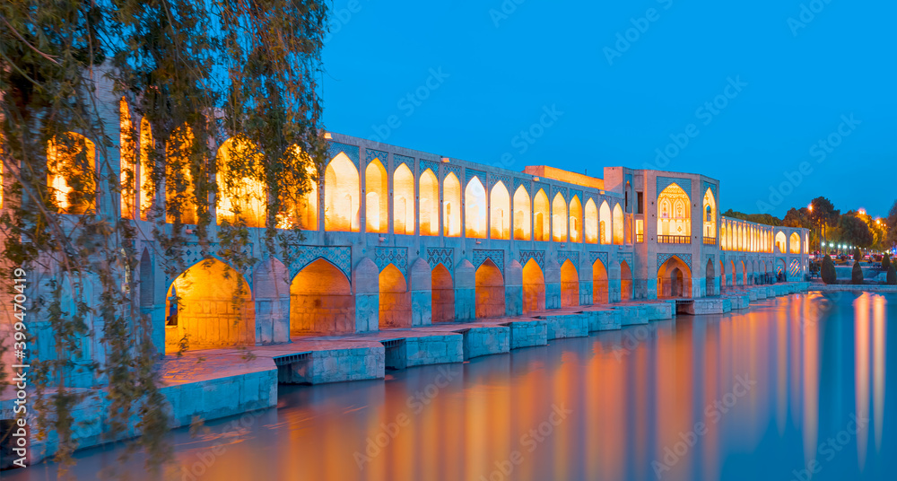 People resting at the ancient Khaju Bridge at twilight blue hour - Isfahan, Iran
