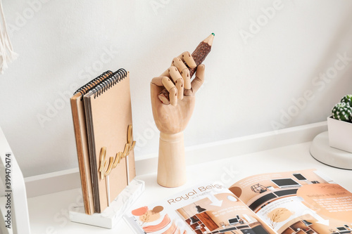 Wooden hand with pencil on table in interior of room