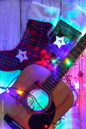 Guitar with Christmas lights and socks on wooden background