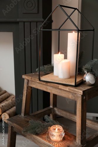 Burning candles with Christmas decor on step ladder