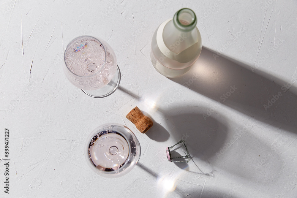 drink, alcohol and glassware concept - wine glasses and open champagne bottle dropping shadows on white surface drink, alcohol and glassware concept - wine glasses and open champagne bottle dropping shadows on white surface