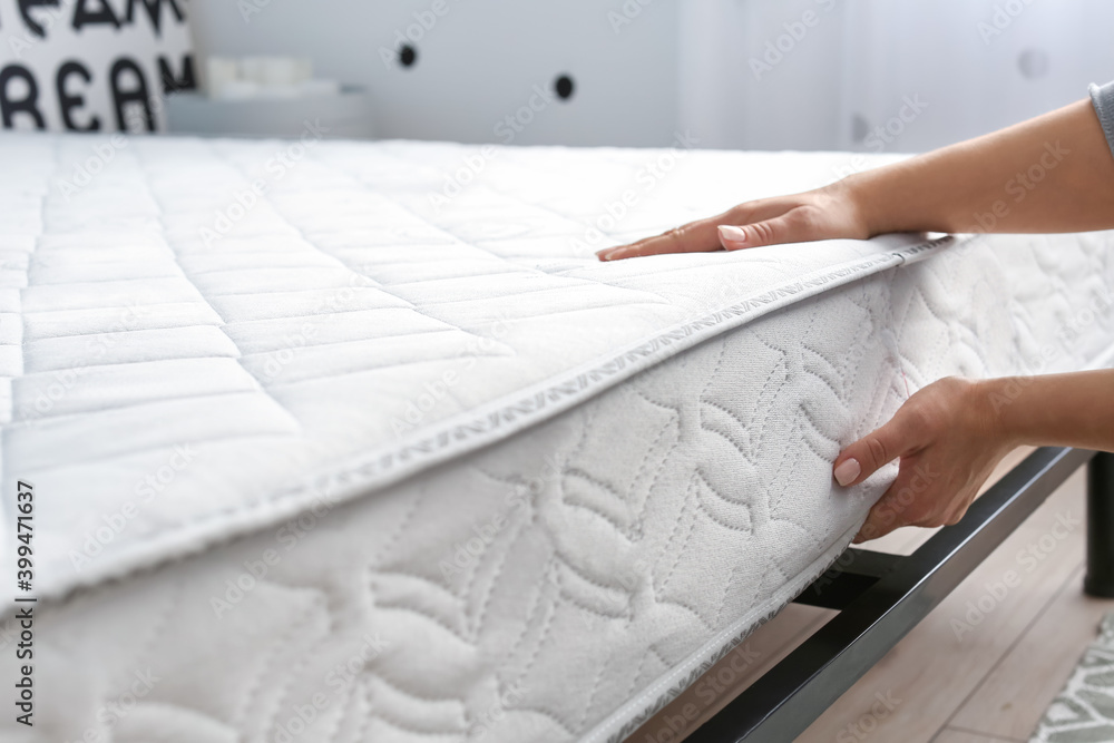 Woman putting soft orthopedic mattress on bed Stock Photo Adobe Stock