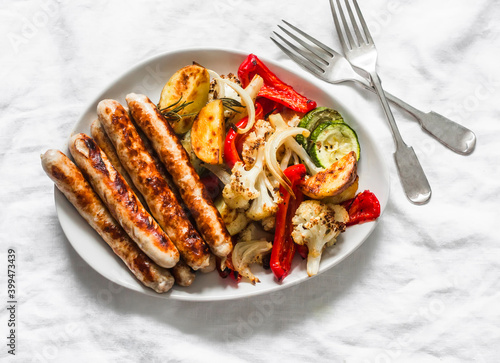 Grilled turkey sausages and roasted vegetables on a light background, top view. Delicious lunch, tapas, appetizer