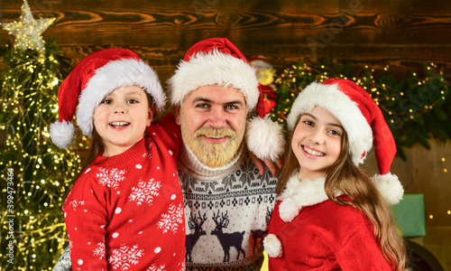 small girls love their father. dad and daughters decorate home. bearded santa man with kids. christmas tree with lights. perfect winter. new year is coming. happy family celebrate xmas