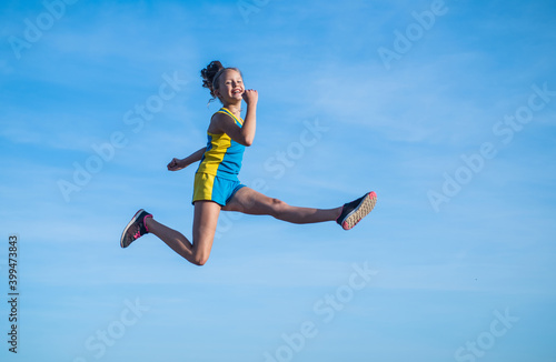 cheerful child athlete or gymnast jump on sky background, energy