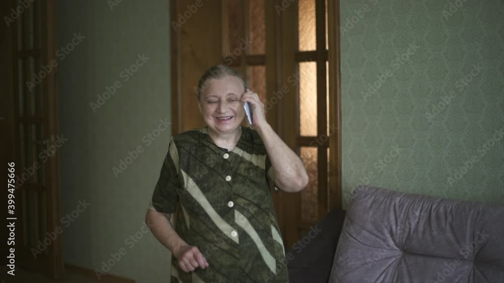Grandma emotionally talks on her cell phone and shows super. An elderly woman smiling talking on a smartphone and showing super. Close-up portrait of the senior woman talking on the phone, smiling and Grandma emotionally talks on her cell phone and shows super. An elderly woman smiling talking on a smartphone and showing super. Close-up portrait of the senior woman talking on the phone, smiling and
