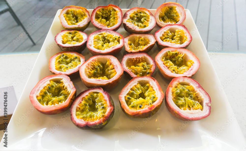 Half cut passion fruits on white plate. Ripe passion fruit isolated on table. Half cut passion fruits on white plate. Ripe passion fruit isolated on table.