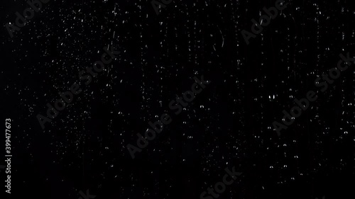 Slow motion shooting of water drops on glass black background