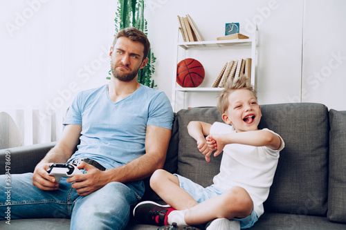 Father and his little son playing video games together at home